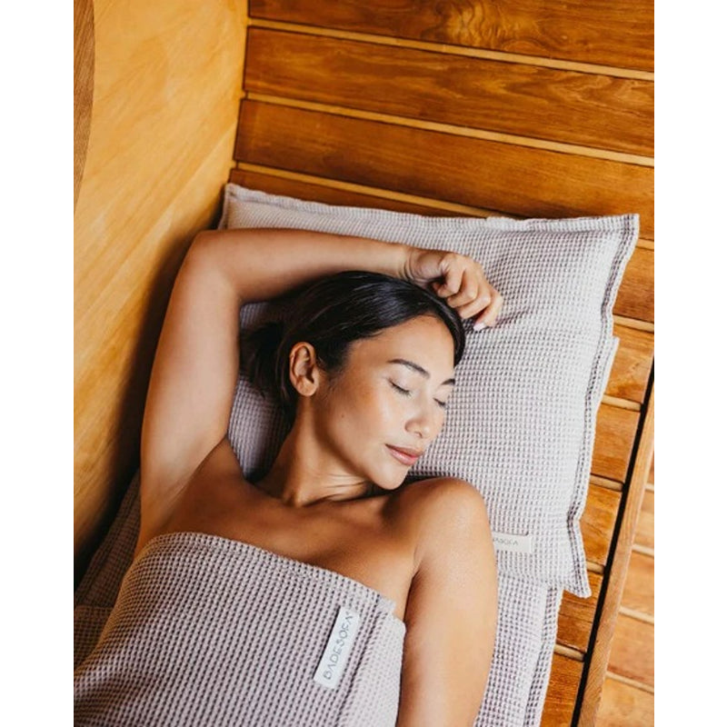 Frau liegt entspannt auf dem Badesofa Saunasofa Set Long in Nature – Wellnessmoment in der Sauna mit gepolstertem Kissen aus Waffelpiqué